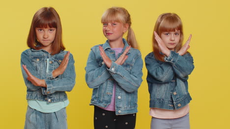 three young girls in denim jackets smiling and posing together on a yellow background