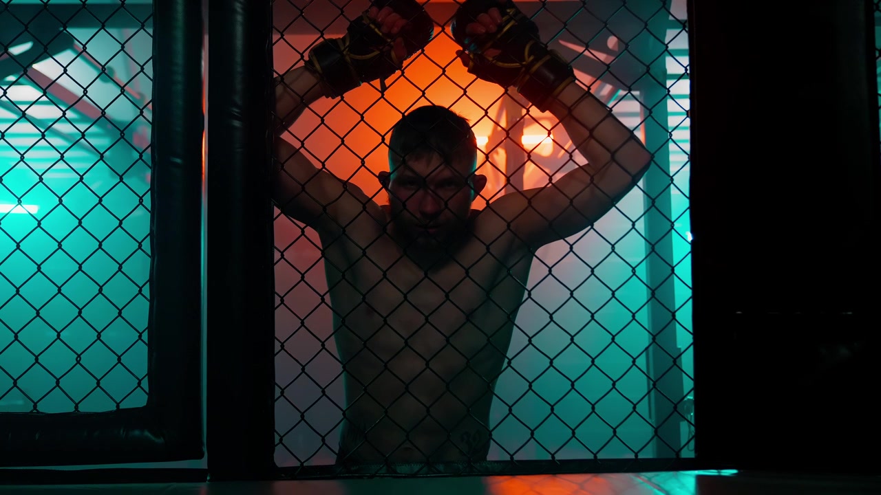 Beslutsom MMA-kæmper står i bur med dramatisk belysning