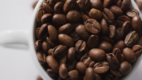 video of cup of roasted brown coffee beans on white background