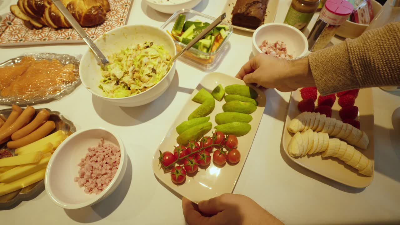 Vídeos stock convidativos mostrando mãos servindo comida em um buffet farto com saladas, legumes, linguiças, queijo e frutas, simbolizando variedade, refeições compartilhadas, hospitalidade e refeições informais