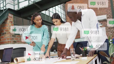 Animation-Von-Social-Media-Symbolen,-Die-über-Verschiedenen-Kollegen-Schweben,-Die-Im-Büro-über-Einen-Plan-Diskutieren