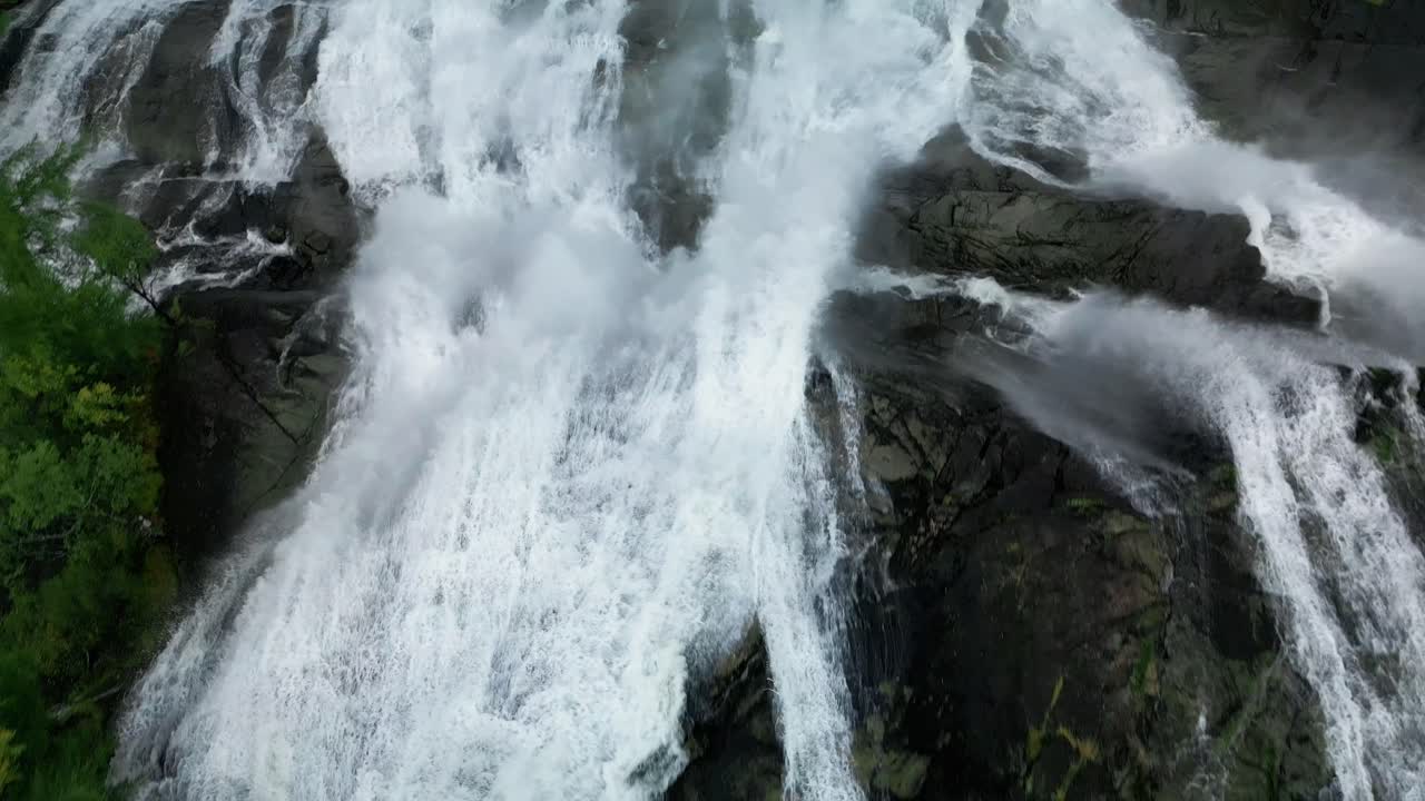 cascada rugiente filmada desde arriba en la naturaleza áspera de noruega con una carretera volando sobre ella