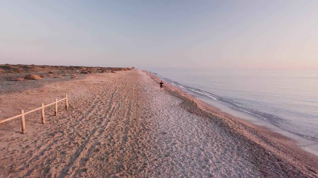 Young runner man training on beautiful sunset at beach