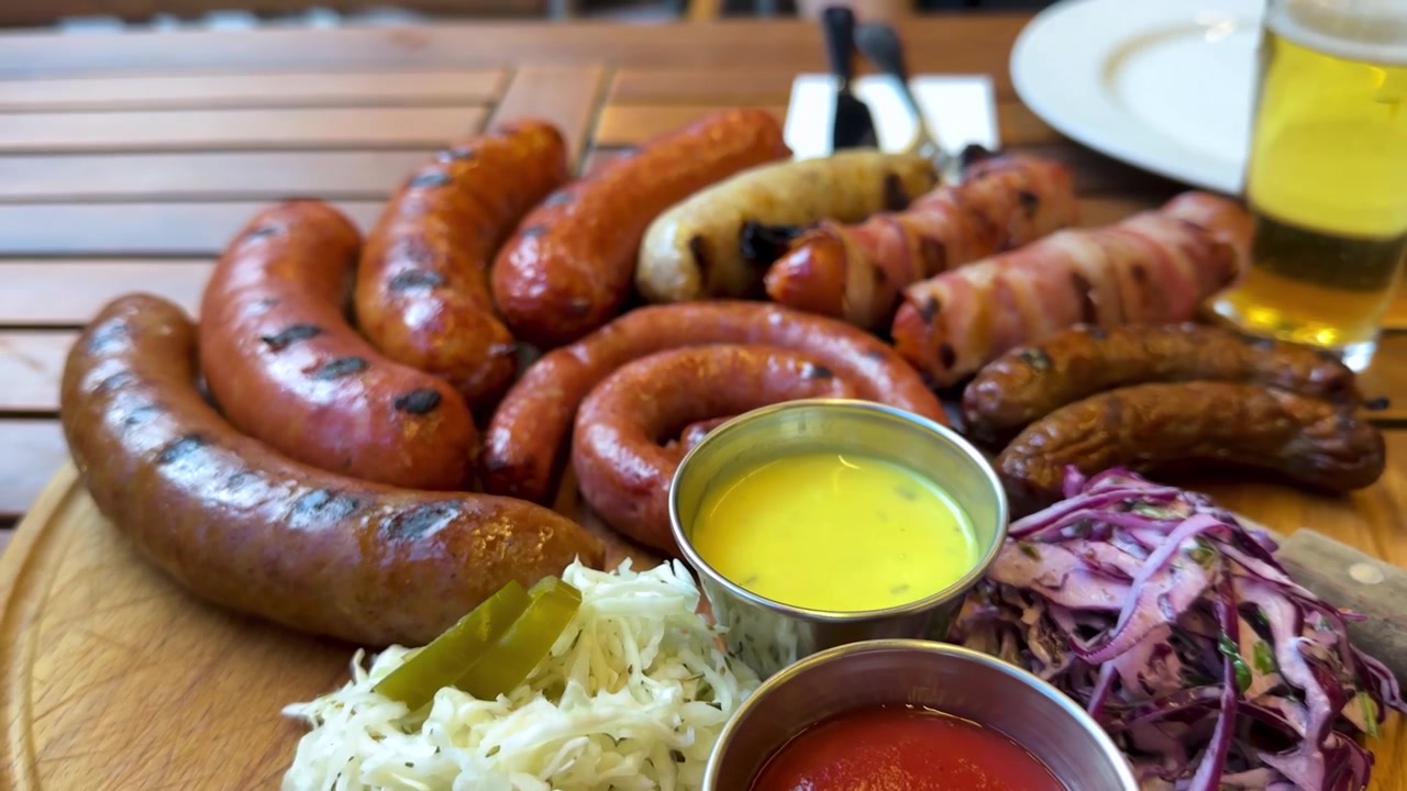 Delizioso piatto di salsicce grigliate naturali biologiche USA Seattle alta qualità sano festa barbecue raduno in sala da pranzo all'aperto vassoio di legno assortimento di birre rustiche carne artigianale affumicata picnic estivo