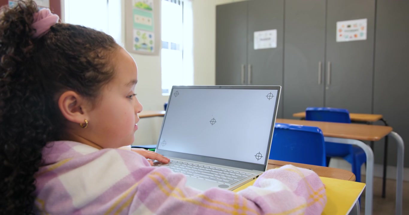 Bambino afroamericano chinato sul laptop al banco di scuola, che digita, reagendo ai pennarelli, con spazio per il testo.