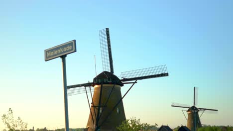 two windmills with stationary blades on the windmill quay in kinderdijk during the day
