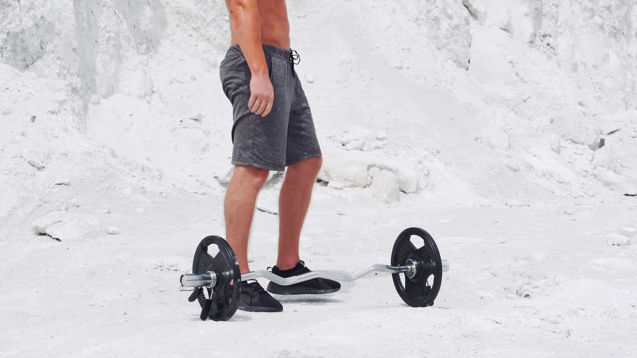 Male bodybuilder doing barbell biceps exercises. Workout in nature