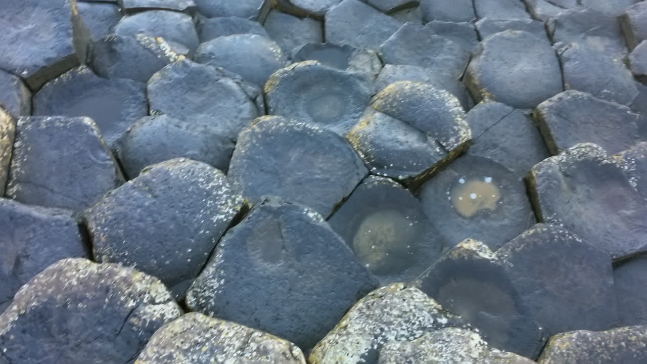 Slow camera movement across hexagonal basalt formations at Giant's Causeway.