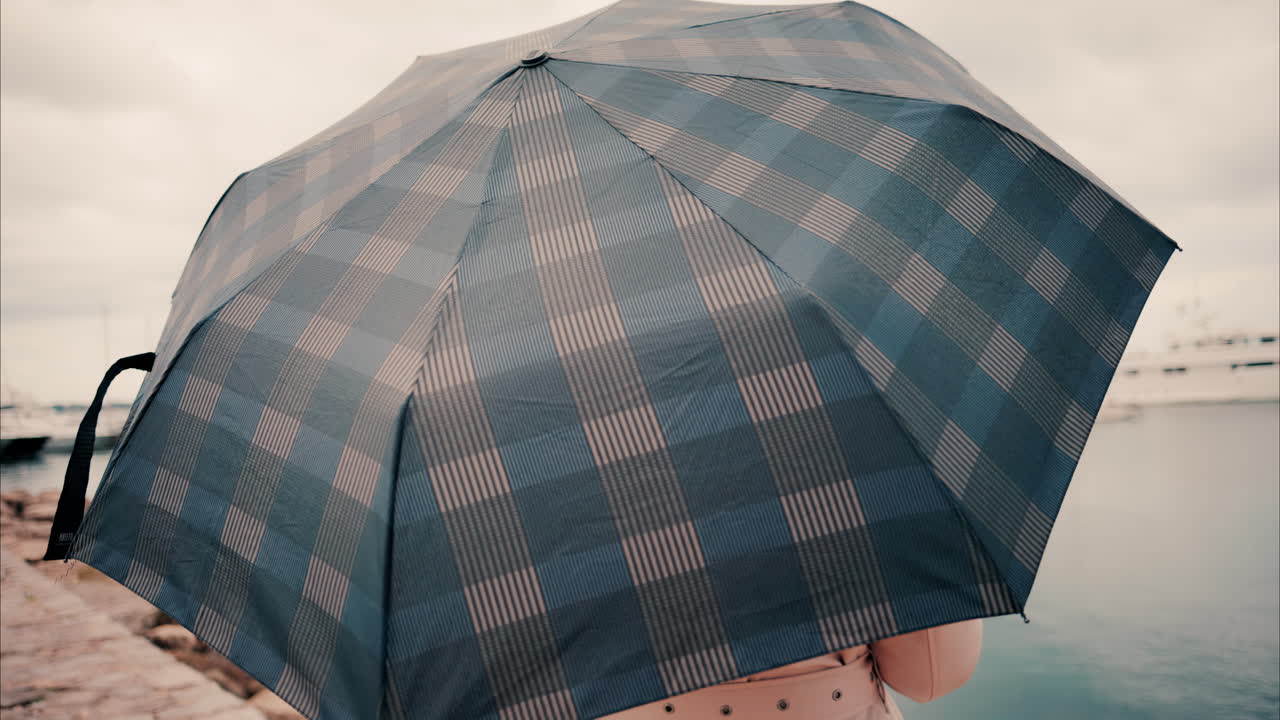 Woman wearing a trench coat looking at the sea in the rain in Cannes, France