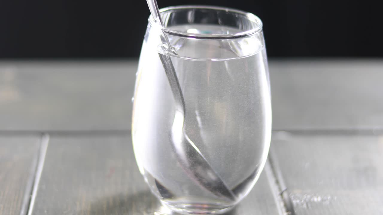 mezclar tinte rojo en un vaso de agua con una cuchara