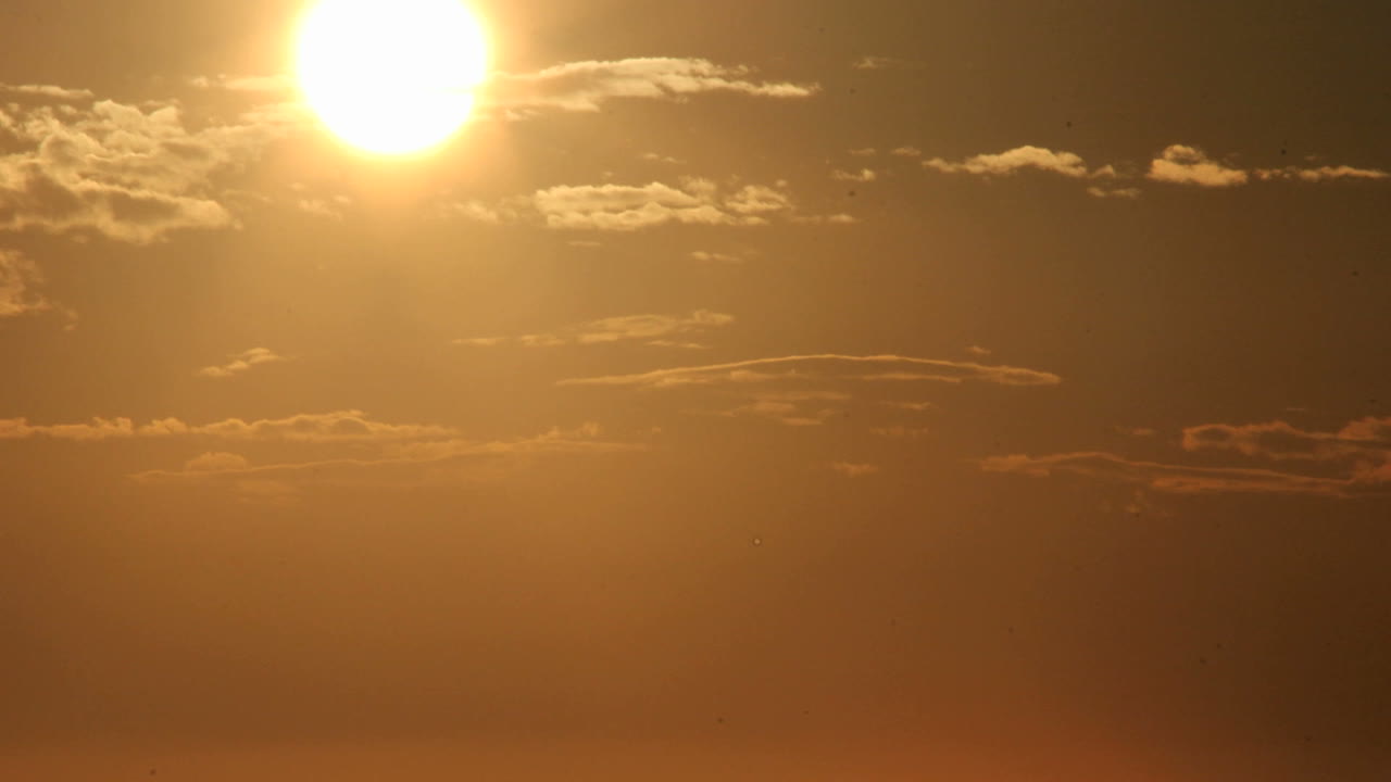 светящееся оранжевое небо темнеет, когда солнце опускается за горизонт