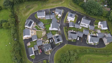 Stunning-aerial-shot-showcasing-new-build-UK-homes-adorned-with-solar-panels,-surrounded-by-lush-greenery-and-modern-amenities