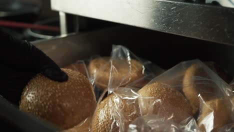 hands with black gloves open drawer and cut hamburger bread with knife. slow-motion