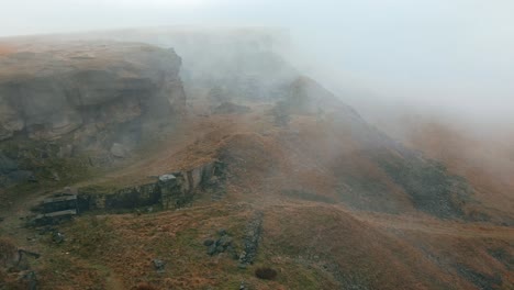 Luftaufnahme-Von-Wolken,-Die-Sich-Langsam-über-Die-Hügel-Bewegen,-Pennines-An-Einem-Nebligen-Morgen,-Goldene-Hügel-Und-Wunderschöne-Felsige-Klippen-Und-Moorlandschaften