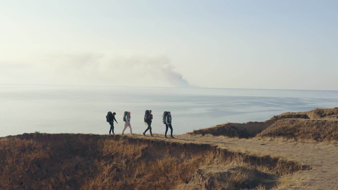 바다 풍경에 대항하여 산에서 고 있는 배을 가진 네 사람