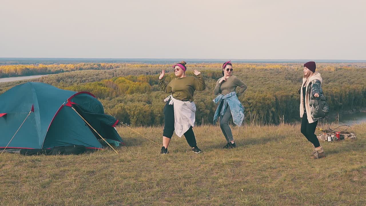 радостные женщины танцуют в лагере на крутом берегу реки в замедленном движении