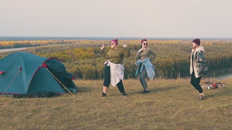 joyful women dance in camp on steep river bank slow motion