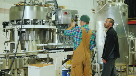 two workers working at the conveyor where bottled sparkling wine work in a small winery