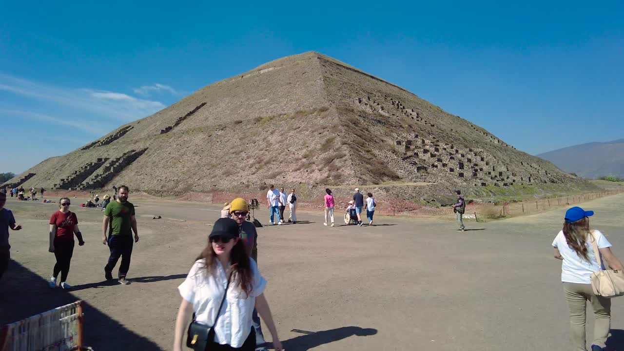 Aztec pyramid with a blue sky in the background and with people walking by, Teotihuacan, Mexico