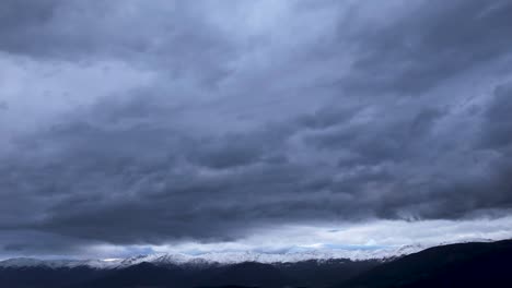 Vuelo-En-Gredos-En-El-Valle-Del-Tietar-Con-Un-Dron-Visualizando-Las-Montañas-Con-Sus-Picos-Nevados-Y-Sobre-Ellos-Una-Gran-Cantidad-De-Nubes-De-Tormenta-Corriendo-En-Un-Hiperlapso-En-Avila-España