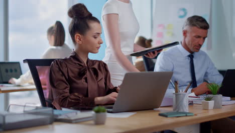 mujer de negocios confiada tomando notas en la computadora portátil