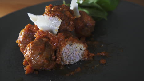 close up of a man eating meatballs in tomato sauce, well presented dish and fine dining experience