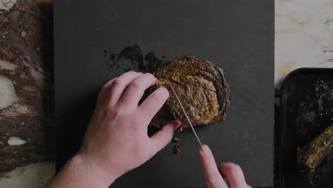 Top-down-shot-of-a-ribeye-steak-being-sliced-on-a-cutting-board