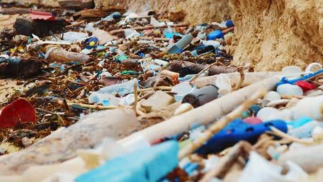 Rack-Fokus-Vom-Vordergrund-Zum-Hintergrund-Von-Plastikmüll,-Der-Am-Strand-Verstreut-Ist