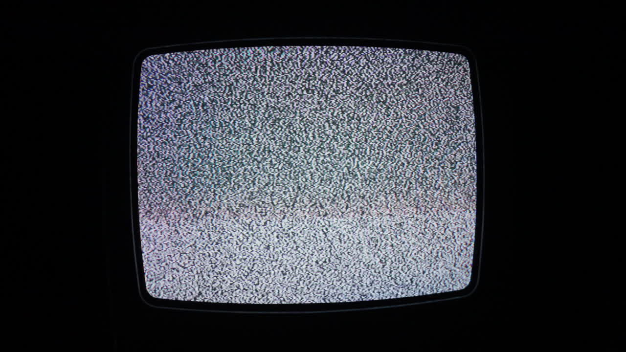 una toma de pantalla completa de un viejo televisor de cátodo que muestra sólo ruido blanco en una habitación oscura y aislada