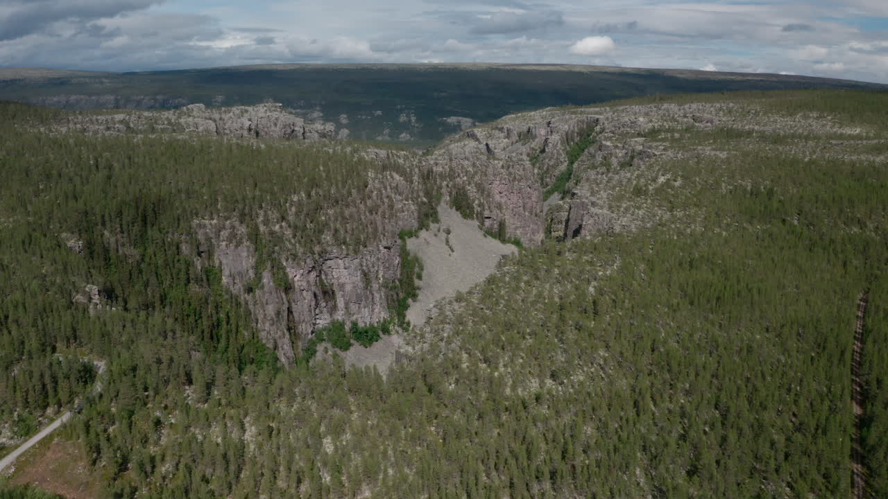 Aerial view of dramatic forest canyon with cliffs and scattered boulders in Norway.