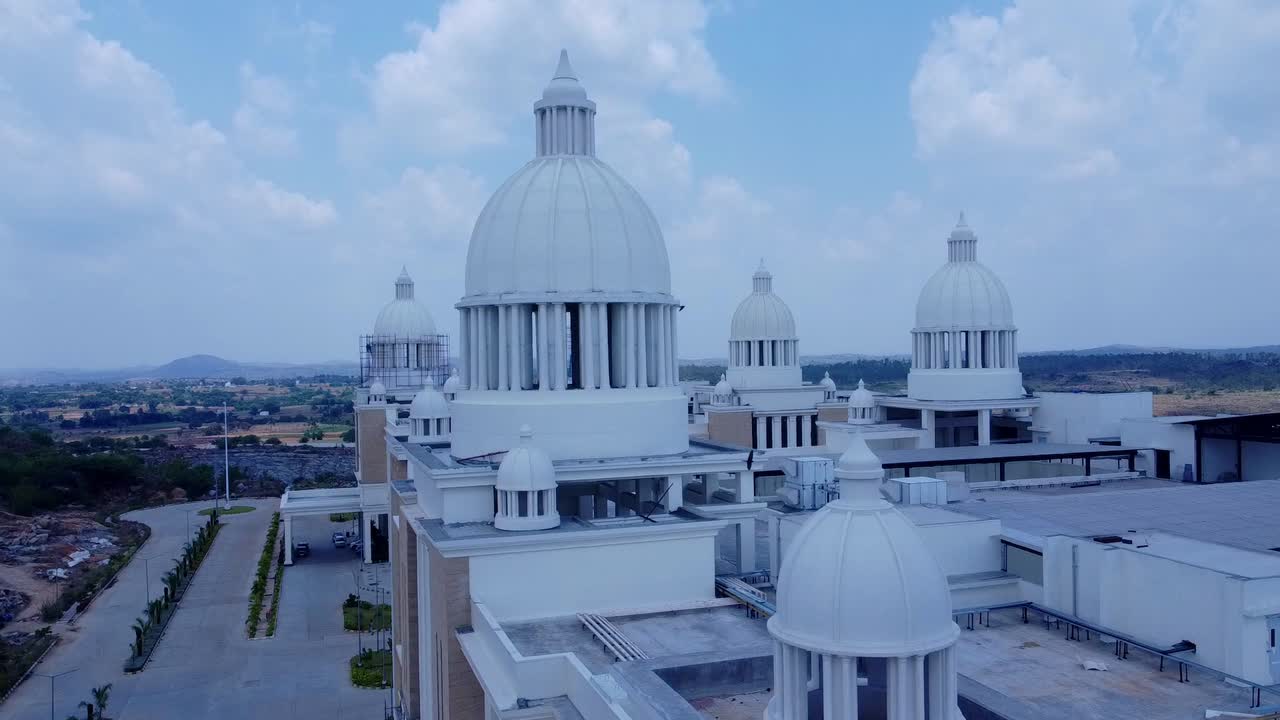 Cinematic aerial view tracking past the towering white domes of a newly constructed, grand university or corporate institution with classical-inspired architecture