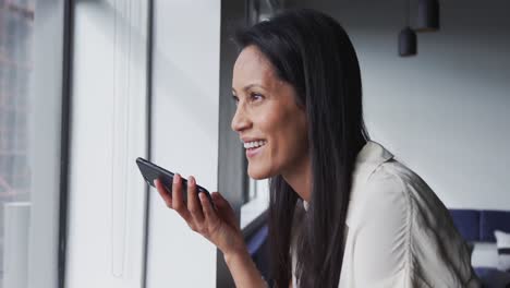 smiling mixed race businesswoman standing talking on smartphone in office