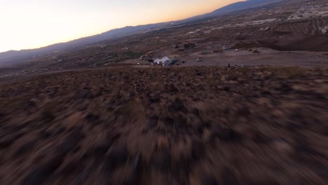 fpv aerial view of desert dry cracked ground fast approaching an event tent