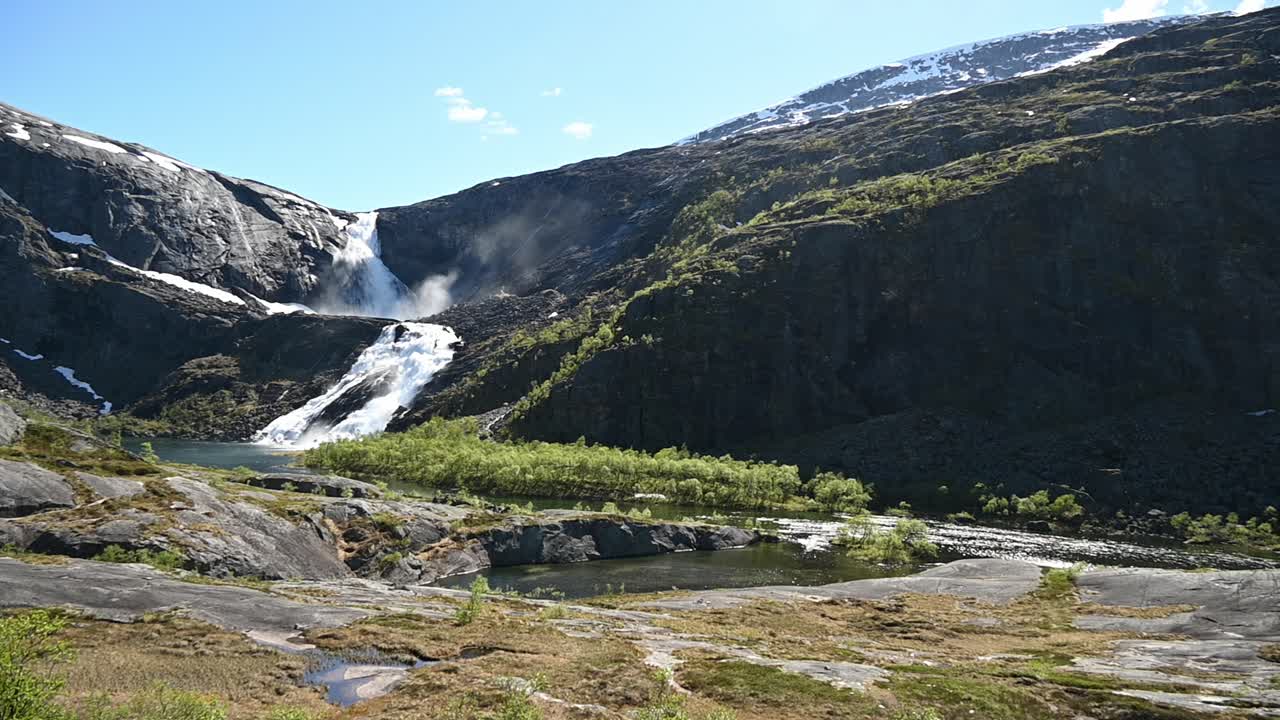 Bjodnabyksetin vesiputous virtaa hidastettuna Nykkjesoyfossenin yläpuolella avaran Hardangerviddenin maiseman ja vihreän laakson Norjan yllä.