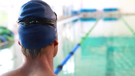 Fit-swimmer-smiling-up-at-camera-by-the-pool