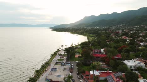 malecon de ajijic city in mexico during foggy day. palm trees at promenade of city. sunset time in mexico. aerial orbit wide shot.