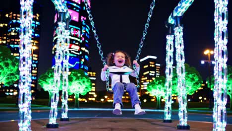 happy child swinging at night in the city