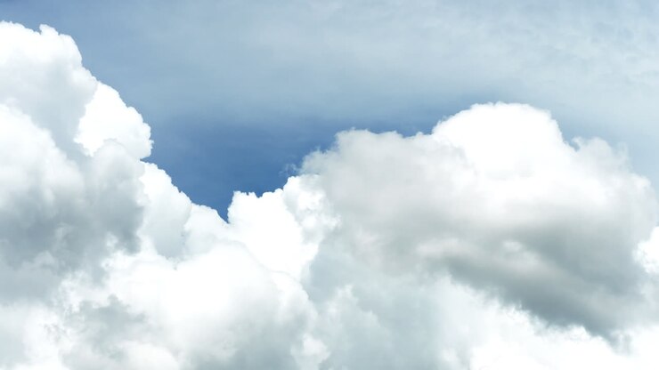 Cumulus clouds move against a clear blue sky
