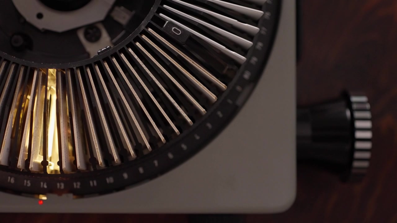 Vintage slide projector shines through mounted slides arranged around a circular carousel, slow zoom in