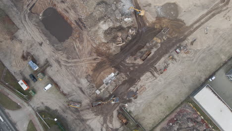 high top down aerial of excavators collecting rubble from demolished building on construction site