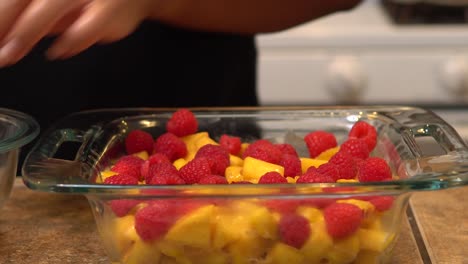 adding raspberries to a homemade crisp recipe - isolated front view