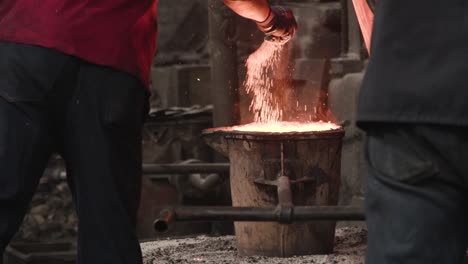 pouring melting iron into a bucket and then adding powdered flux