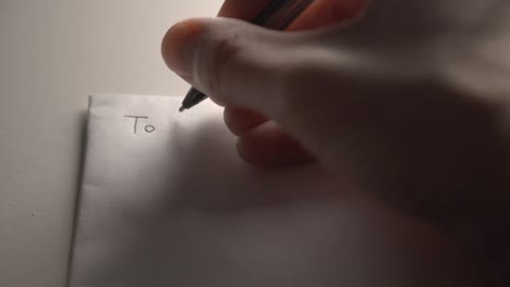 a right-handed person writing on a white paper using an ink pointed pen - closeup shot