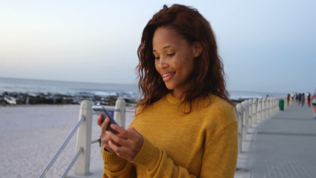 Woman using mobile phone on beach 4k