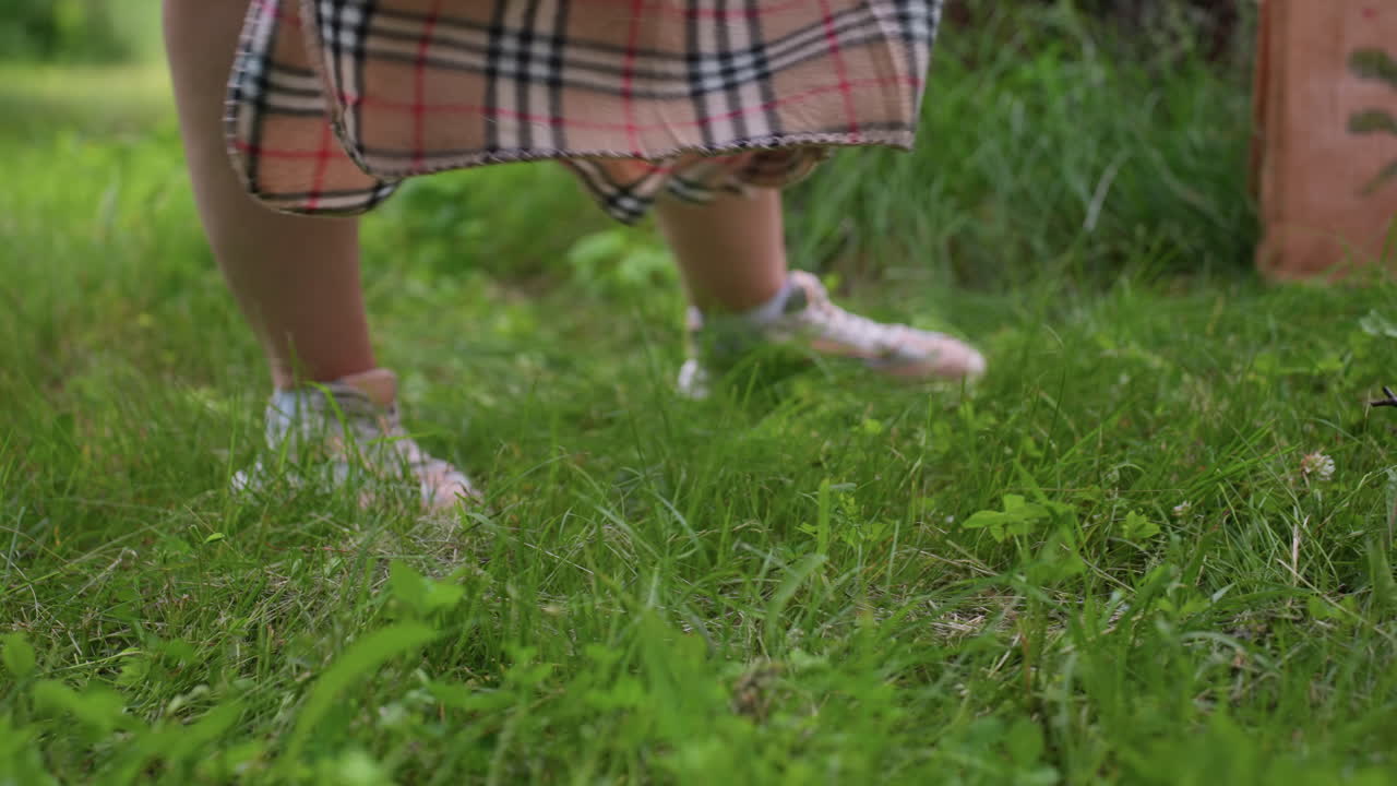 Checker blanket being parked gently on fresh green grass in bright park scene, showing soft fabric movement and vibrant nature details as someone prepares picnic area