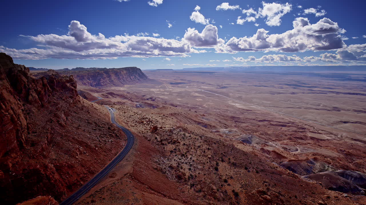 A high-flying drone reveals a rugged road slicing through blazing red cliffs in northern Arizona.