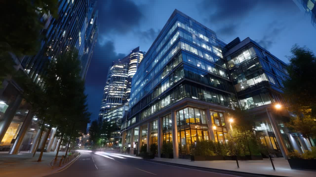 Paisagem urbana noturna com edifícios de vidro modernos iluminados sob um céu azul escuro, com luzes de rua e de veículos criando uma atmosfera vibrante