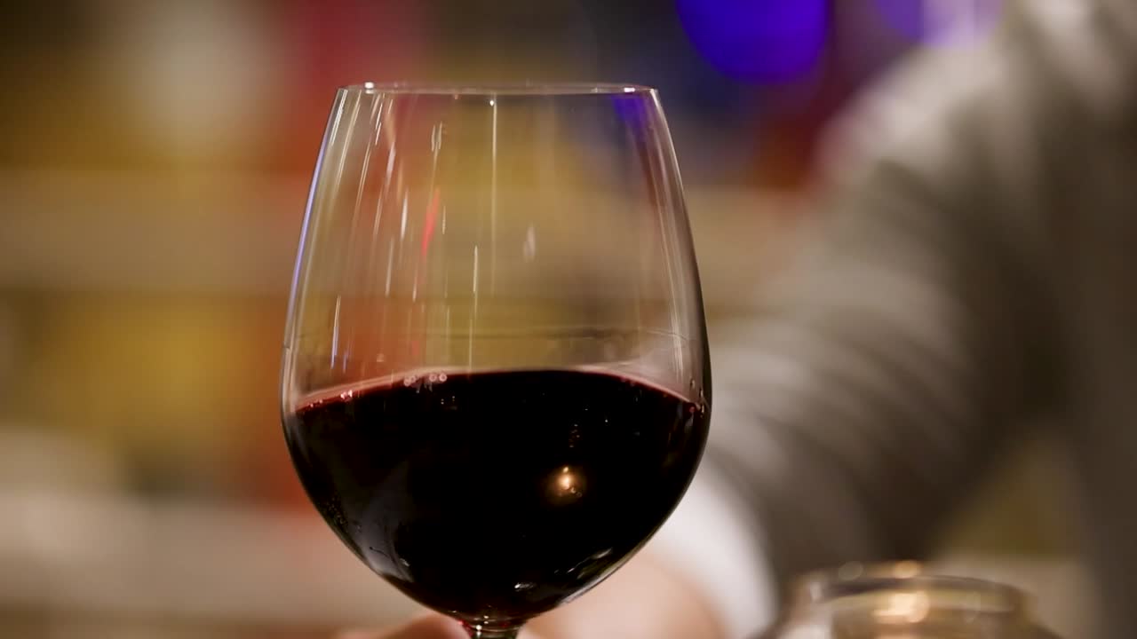 A detailed view of a red wine glass with a softly blurred background, highlighting the rich color and reflections.