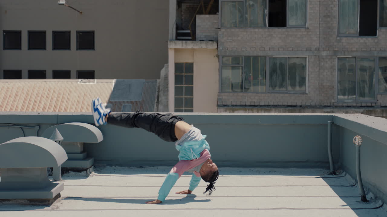 춤추는 남자가 도시의 지붕에서 브레이크댄스를 하고  ⁇ 합 댄서가  ⁇ 드 스탠드로 댄스 루틴을 연습하고 도시에서 프리스타일 동작을 한다