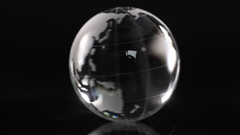 glass transparent ball globe is spinning on black background